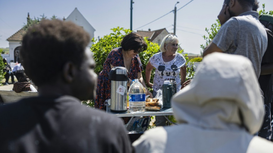 French volunteers hand migrants water beyond the crowded beach